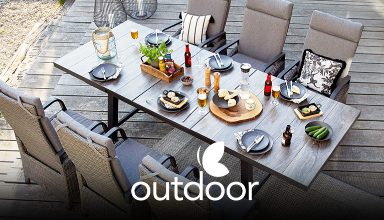 outdoor Gartentische bei Moebel-Shop - Ein von oben fotografierter outdoor Gartentisch aus Holz mit passenden outdoor Gartenstühlen mit grauen Polstern, Tischdekoration, Essen und Getränke auf dem Tisch
