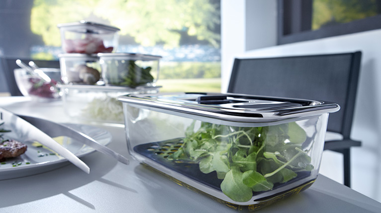 Mehrere WMF-Vorratsdosen mit frischem Salat stehen auf einem Tisch.