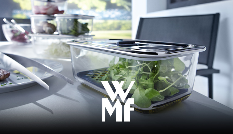 Mehrere WMF-Vorratsdosen mit frischem Salat stehen auf einem Tisch.
