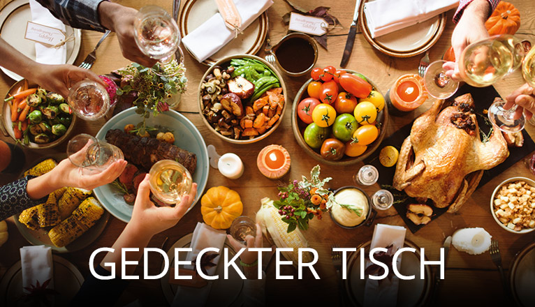 Fröhliche Küchenszene mit drei Personen, die gemeinsam kochen und lachen, umgeben von frischen Zutaten, Kochutensilien und einem Glas Wein, in heller moderner Wohnküche mit viel Tageslicht
