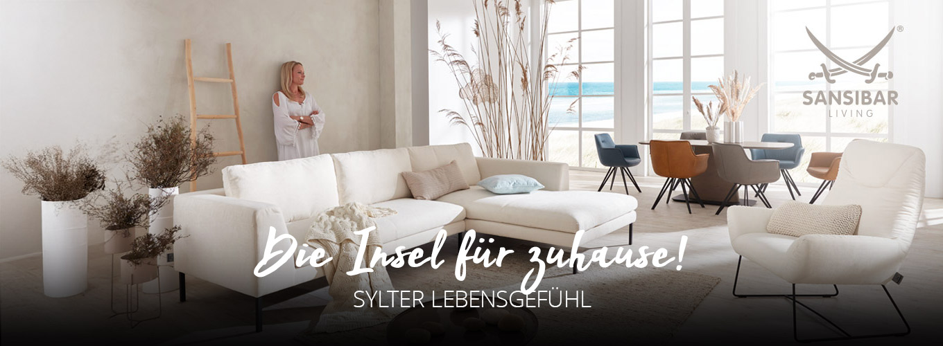 Die Insel für Zuhause - Sylter Lebensgefühl - Ein cremefarbenes Ecksofa in hellem Raum mit großen Sprossenfenstern und natürlicher Dekoration, ein Esstisch mit farbigen Stühlen im Hintergrund
