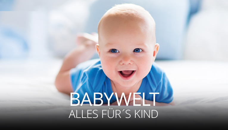 Ein fröhliches Baby in blauem Strampler liegt auf dem Bauch und lächelt in die Kamera, weiche helle Umgebung, Symbol für Geborgenheit und Babywelt, alles für dein Kind.