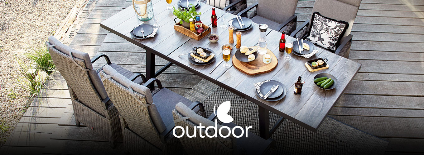 outdoor Gartentische bei Moebel-Shop - Ein von oben fotografierter outdoor Gartentisch aus Holz mit passenden outdoor Gartenstühlen mit grauen Polstern, Tischdekoration, Essen und Getränke auf dem Tisch