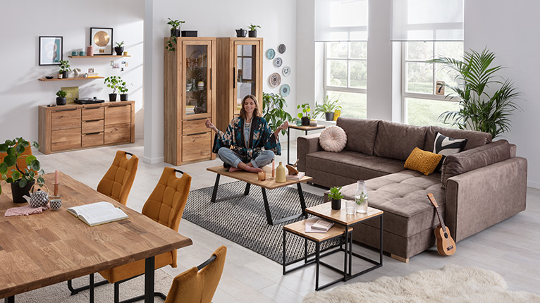 self Wohnen bei Moebel-Shop - Wohn- und Esszimmer mit ausziehbarem Ecksofa in Braun, Couchtischen mit Metallgestell, Essgruppe in Holzoptik und Vitrinen. Wandregal und Sideboard ergänzen das moderne Raumkonzept.