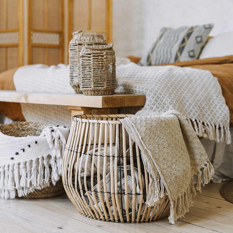 Gemütliches Schlafzimmer im Boho-Stil mit naturfarbenen Textilien, Rattanmöbeln, dekorativen Körben, Holzelementen und harmonischen Wohnaccessoires in warmen Naturtönen.