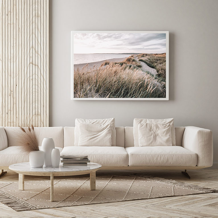 Wohnzimmer im skandinavischen Stil mit hellem Sofa, Naturmaterialien, dezenten Farben, Landschaftsbild und minimalistischen Wohnaccessoires für eine ruhige Atmosphäre.