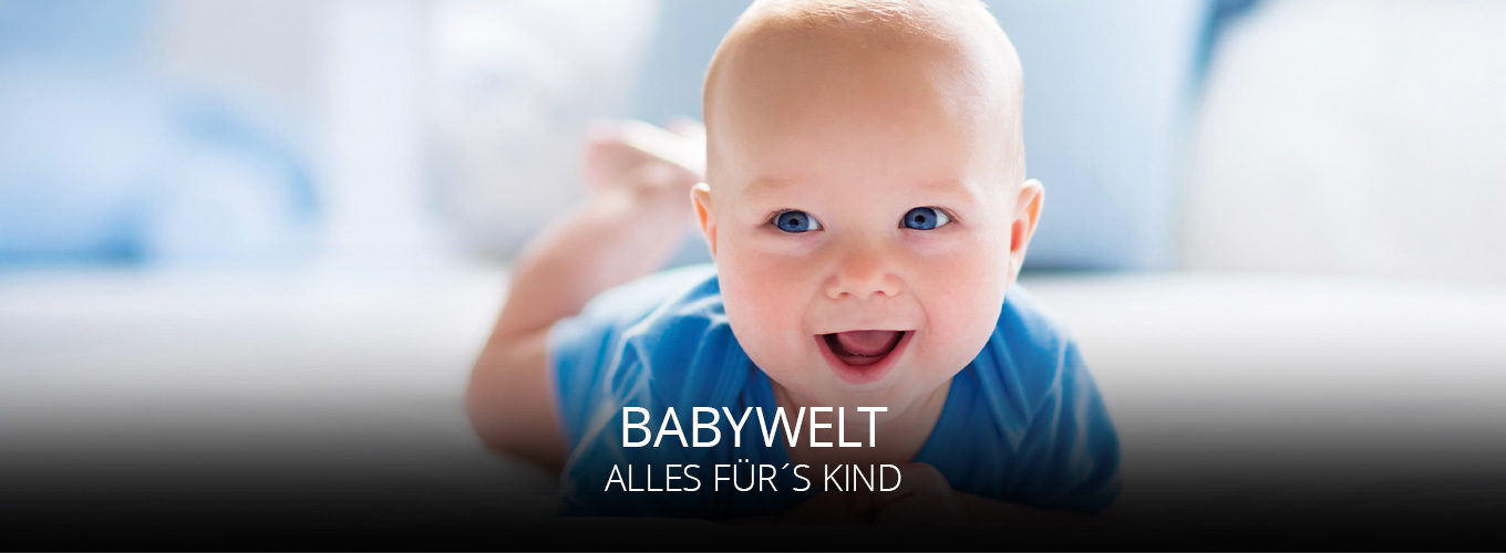 Ein fröhliches Baby in blauem Strampler liegt auf dem Bauch und lächelt in die Kamera, weiche helle Umgebung, Symbol für Geborgenheit und Babywelt, alles für dein Kind.