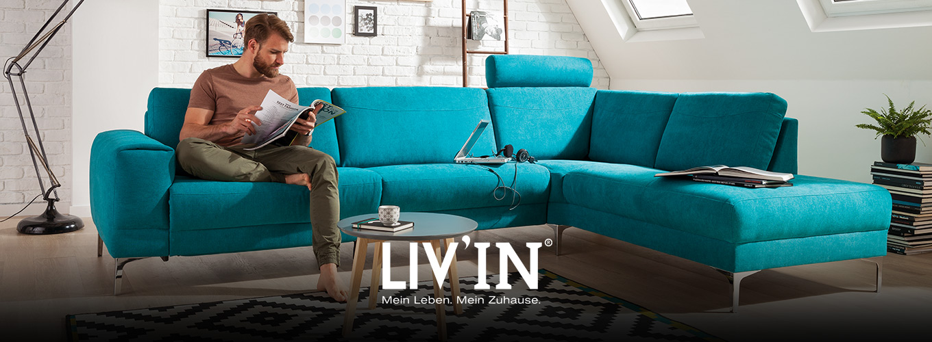 LIV’IN Polster bei Moebel-Shop - Ecksofa in Türkis mit verstellbarer Kopfstütze und filigranen Metallfüßen. Runder Beistelltisch aus Holz und Teppich im grafischen Schwarz-Weiß-Muster ergänzen das moderne Ambiente.