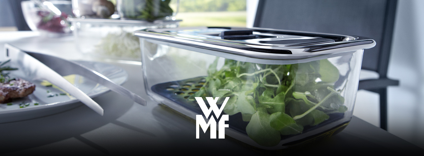 Mehrere WMF-Vorratsdosen mit frischem Salat stehen auf einem Tisch.
