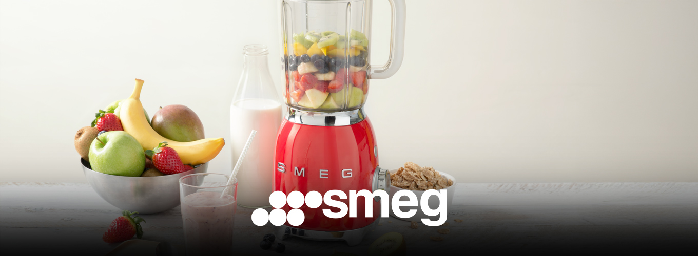 smeg Standmixer bei Moebel-Shop – Roter SMEG Standmixer mit einem gemixten Smoothie in einem Glas mit Strohhalm, eine Schale mit Obst, eine Flasche Milch und eine Schale mit Cerealien stehen daneben