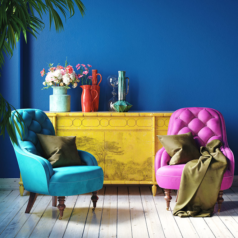 Wohnzimmer im Maximalismus-Stil mit farbenfrohen Sesseln, gelbem Sideboard, dekorativen Vasen, Blumen und kräftigen Farben für einen ausdrucksstarken Look.