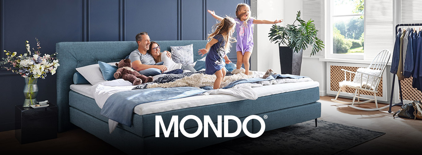 MONDO Schlafen bei Moebel-Shop - Eine Familie mit zwei Kindern in einem blauen MONDO Familien-Boxspringbett. Die Eltern liegen Arm in Arm und schauen lachend zu, wie ihre Kinder auf dem Bett freudestrahlend hüpfen.