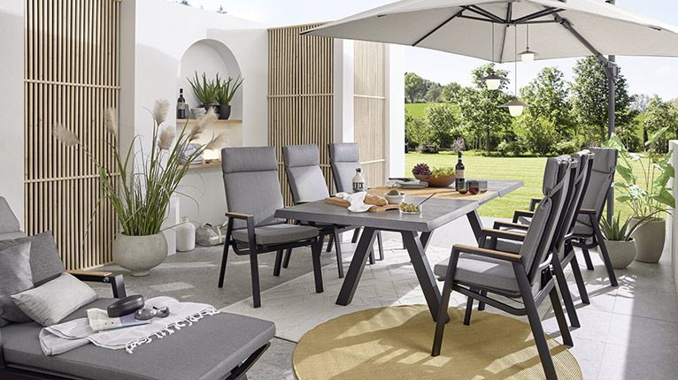 MONDO Garten bei Moebel-Shop - Eine Gartenterrasse mit MONDO Gartenmöbeln in Grau und Anthrazit und einem großen, geöffneten Sonnenschirm in Creme