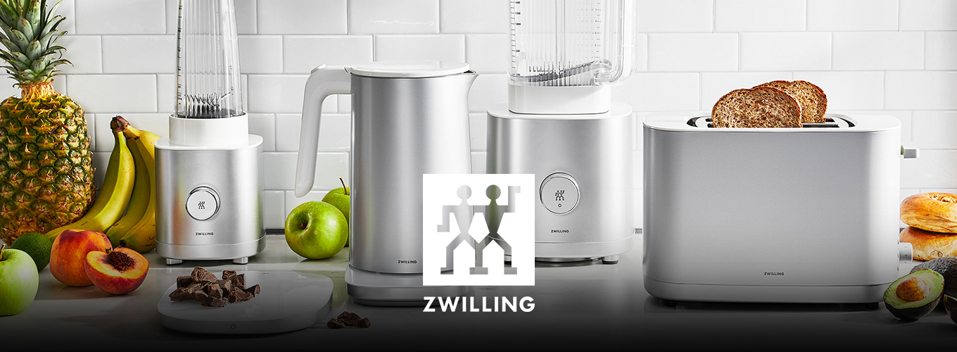 ZWILLING Enfinigy-Serie mit kleinem Standmixer, Wasserkocher, großem Standmixer und Toaster; umgeben von Obst und Brot.