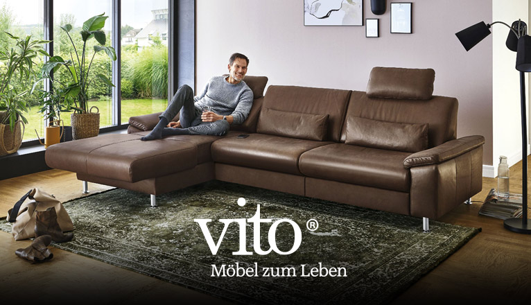 vito Sofas bei Moebel-Shop - Ein Mann sitzt entspannt auf einem braunen vito Ledersofa mit einem Glas Wasser in der Hand