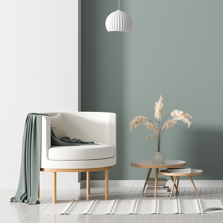 Wohnzimmer im minimalistischen Stil mit hellem Sessel, Beistelltischen, dezenter Dekoration, Pendelleuchte und harmonischen Naturfarben für eine ruhige Atmosphäre.