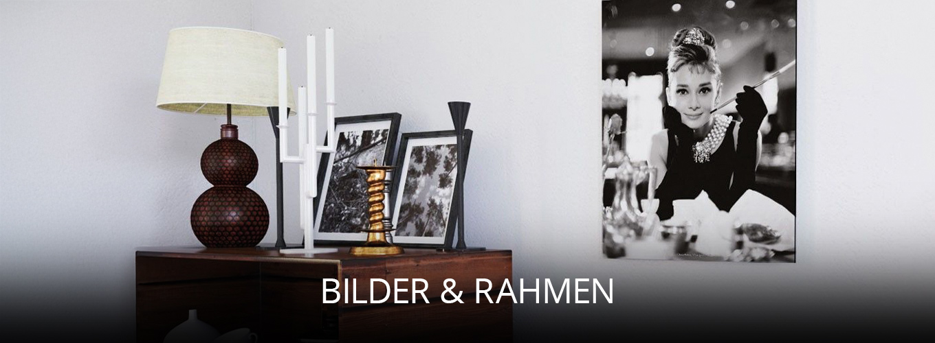 Dekorativer Wohnbereich mit Wandbild in Schwarz-Weiß, mehreren gerahmten Fotos auf einer Kommode sowie stilvollen Accessoires wie Lampe und Kerzenhaltern, die eine elegante Atmosphäre schaffen